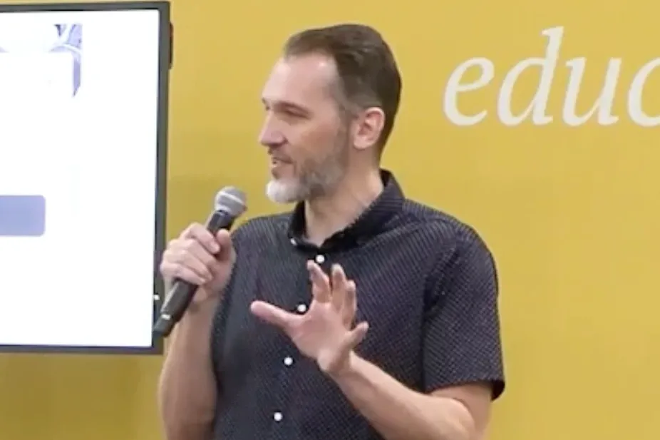 Brian Schmitt speaking with a microphone on the education stage at Outdoor Retailer Summer 2023